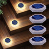 A set of solar powered LED step and path lights with blue solar panels illuminating wooden steps.