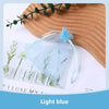 Light blue organza drawstring jewelry gift bags with dried herbs displayed on a wooden surface.