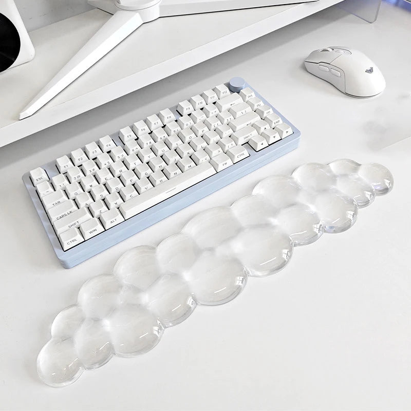 A set of clear, cloud-shaped ergonomic wrist rests for a keyboard and mouse are displayed on a white desk.