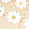 A collection of white daisy flower shaped disposable party tableware, including plates and sticks.