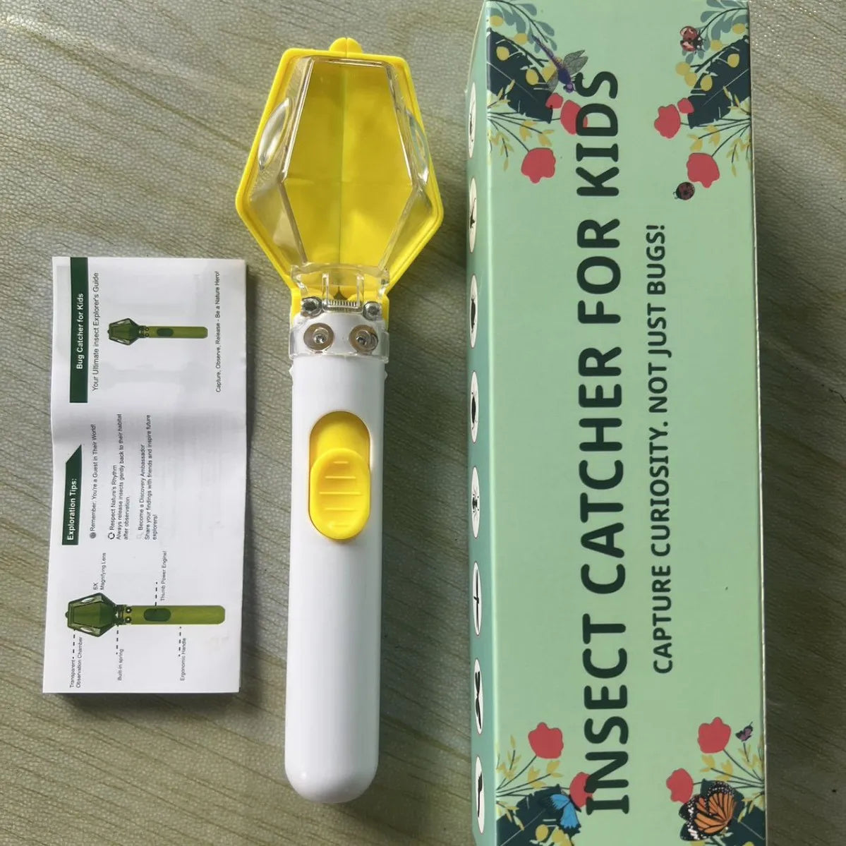 A yellow insect catcher and magnifying viewer for kids is shown next to its packaging box.