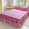 Pink floral print bed skirt and pillowcase set on a bed with a light purple frame.