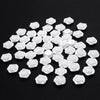 A pile of 100 white acrylic pearl spacer beads for jewelry making scattered on a black surface.