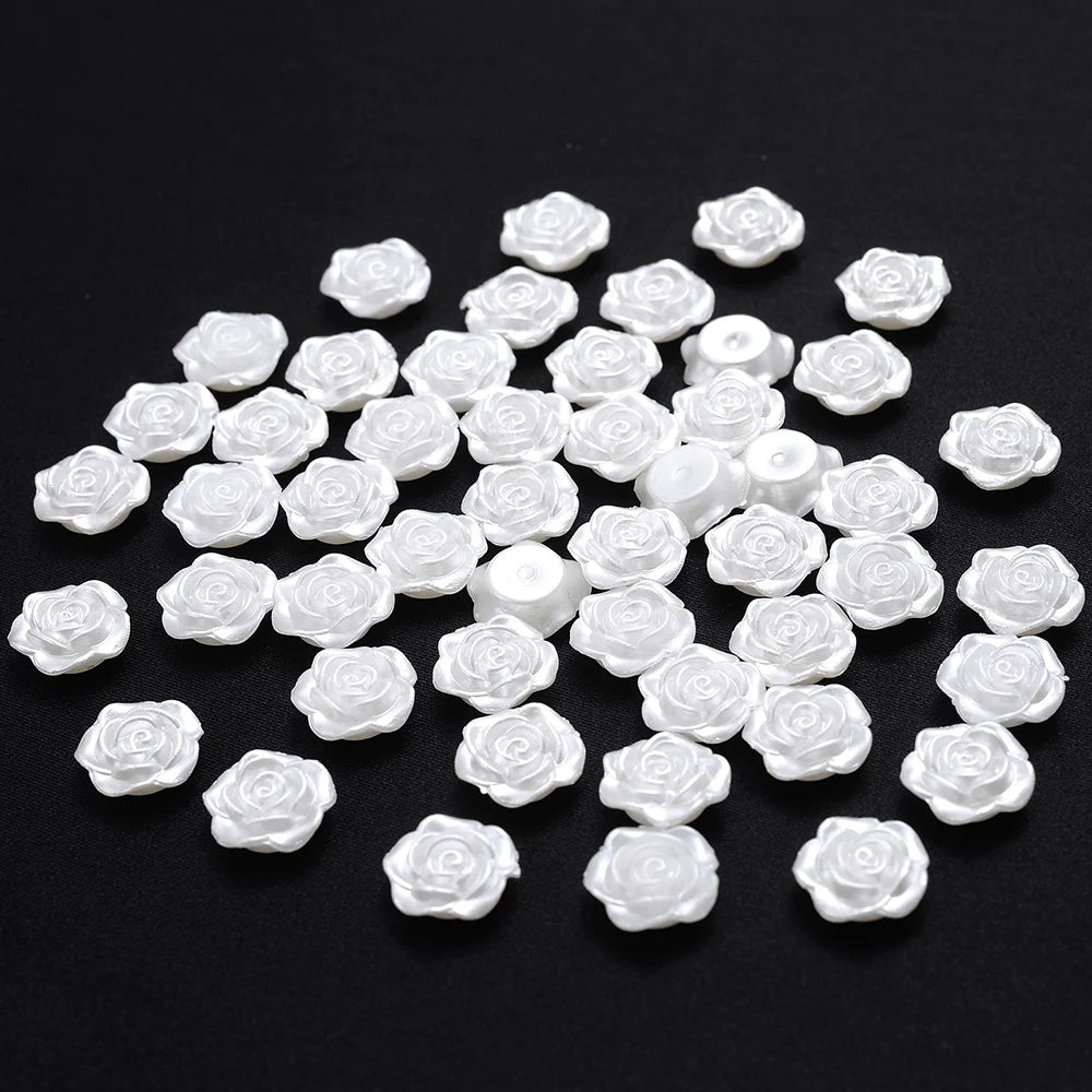 A pile of 100 white acrylic pearl spacer beads for jewelry making scattered on a black surface.