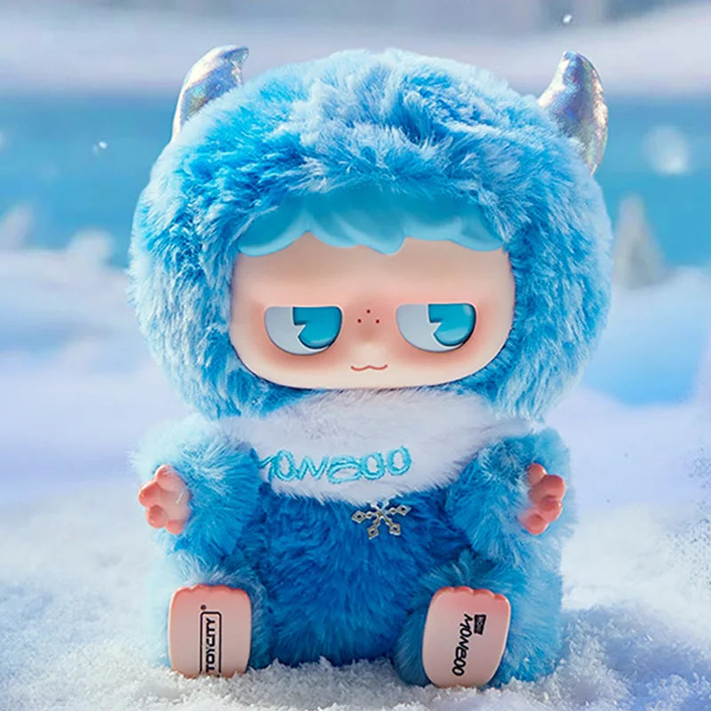 A fluffy blue MONBOO collectible blind box featuring a face and white trim, resting in the snow.
