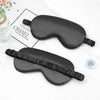 A black silk sleep mask is shown on a white background next to a Chanel branded card.
