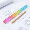 A colorful geometric cube drawing tool with a straight edge is shown next to technical drawings on paper.