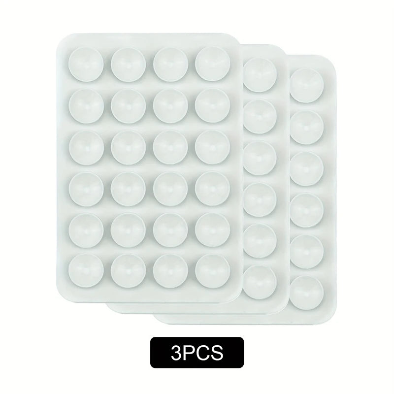 A pack of three white reusable silicone suction phone mounts in a plastic tray.