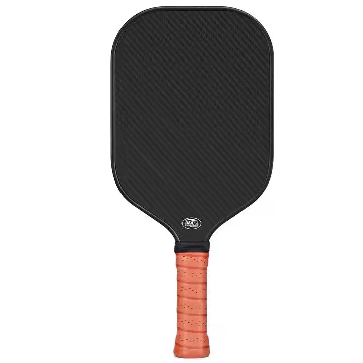 A black pickleball paddle with an orange grip and carbon fiber face.