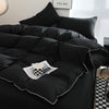 Black duvet cover set with matching pillowcases and a white and black checkered mug on the bed