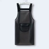 A black waterproof kitchen apron hanging against a light gray background.