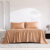 Luxuriöses braunes Bambusbettlaken-Set über einem Bett in einem hellen, minimalistischen Raum.