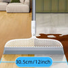 A close-up view of a silver detachable broom with a silicone scraper on a wooden floor.