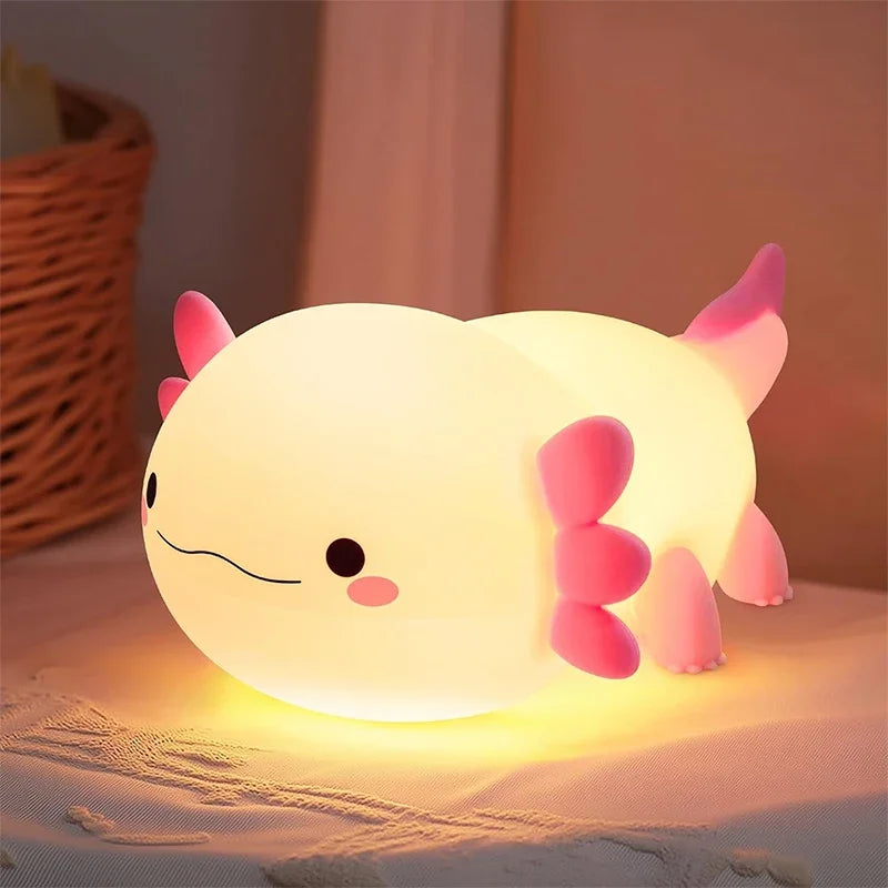 A pink silicone night light shaped like a cute animal resting on a white fabric surface.