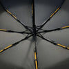 A black windproof umbrella with yellow accents is shown open, displaying its spokes and canopy.