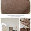 A close-up of a brown jacquard fleece sofa cover with a textured pattern and light beige piping.