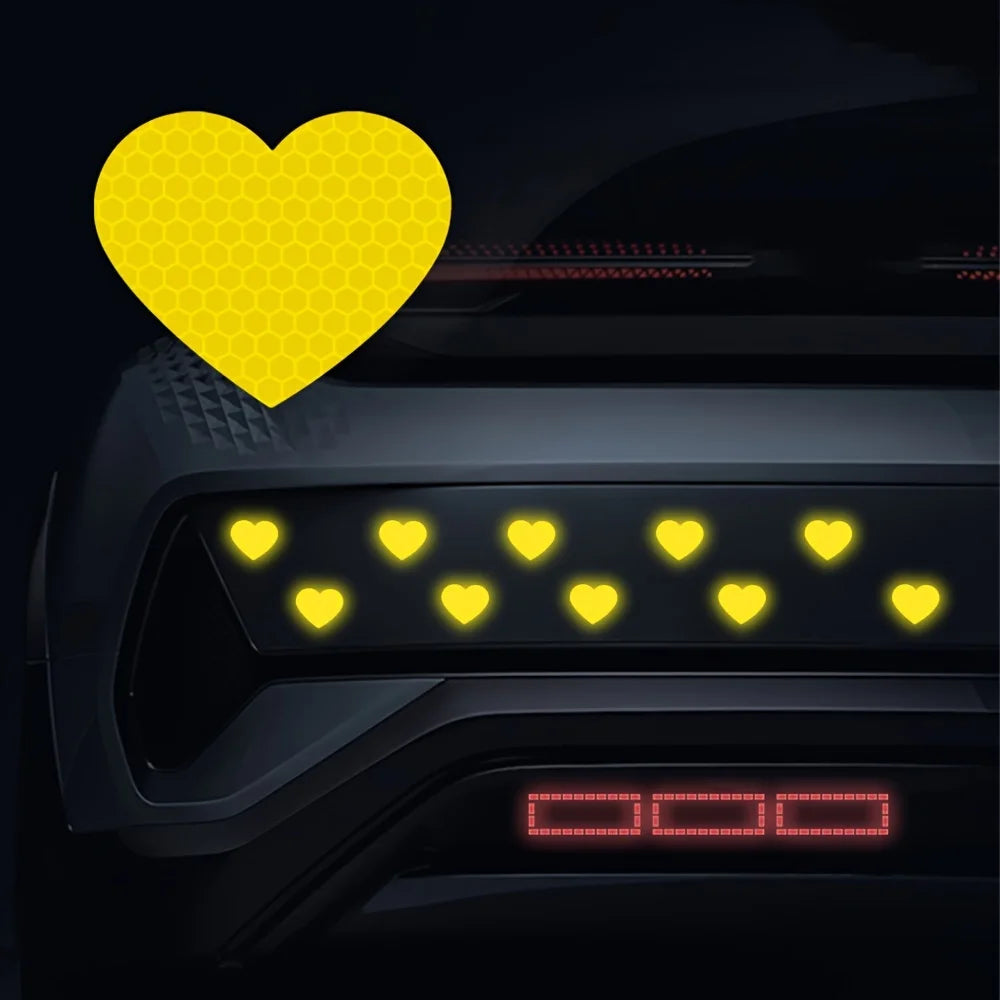 Yellow heart stickers placed on a dark car surface, highlighting reflective safety features.