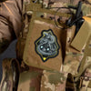 A tactical snake morale patch with a black and yellow design is attached to a camouflage fabric item.