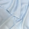 A close-up of a light blue luxury bamboo flat sheet fabric draped and folded.