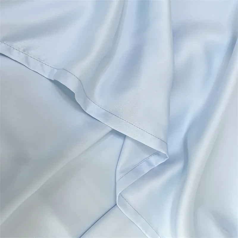 A close-up of a light blue luxury bamboo flat sheet fabric draped and folded.