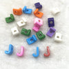 A collection of 10 mixed alphabet letter beads in various colors and shapes scattered on a white, fluffy surface.
