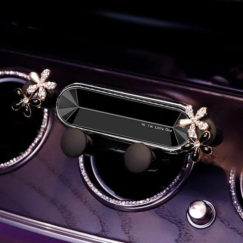 A crystal flower gravity car phone holder with auto-lock displayed on a purple surface.