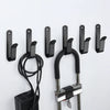 Black snowboard wall mount clips with screws and a coiled cord for mounting equipment