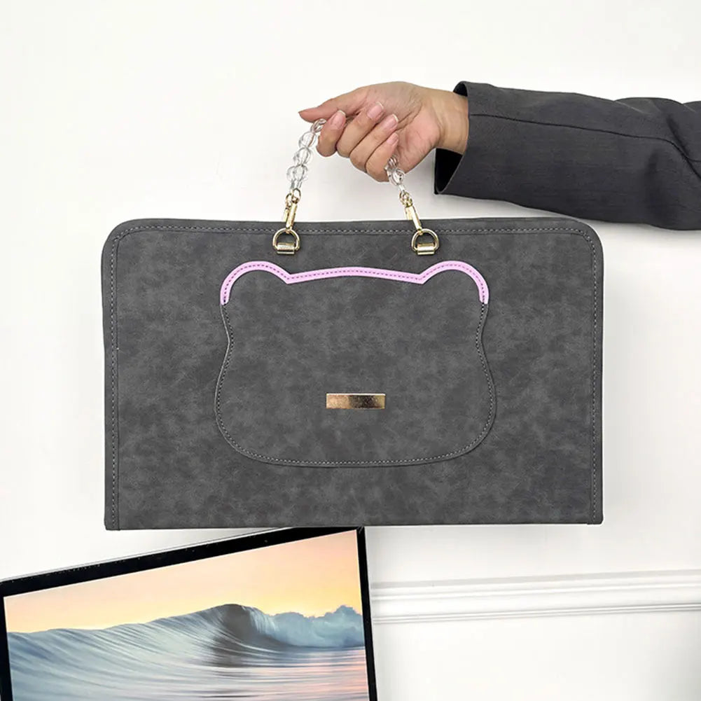 A gray water-resistant laptop briefcase with a cat face design is held by a hand.