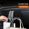 A hand is shown using a co-pilot hook to hang a white handbag from the seat back of a car.