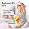 A baby is holding a yellow and pink sensory toy with a hanging crab design, used for fine motor skill exercises.