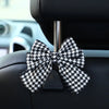 A black and white checkered bow-shaped car seat back hook with storage mounted on a vehicle interior.