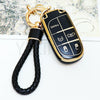 A black and gold durable TPU car key fob cover with various function buttons attached to a black braided leather strap.