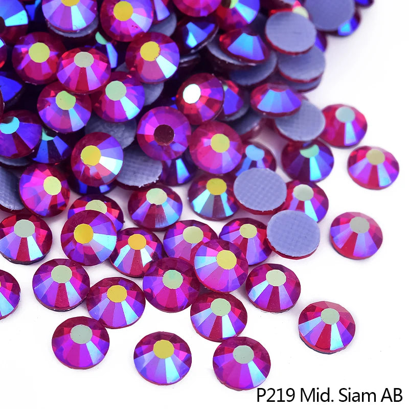 A close-up of various iridescent and holographic rhinestones in shades of purple, pink, and blue.