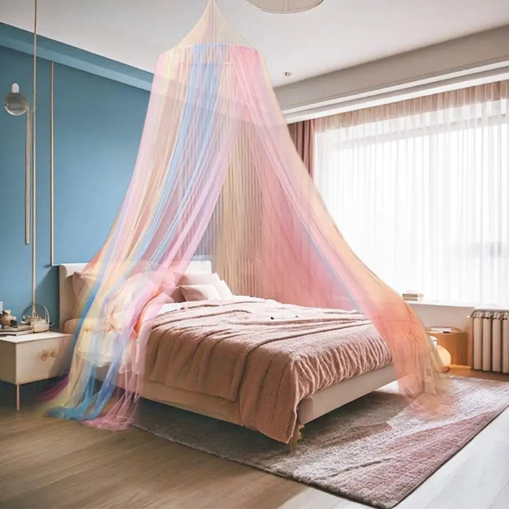 A bed draped with a sheer rainbow colored hanging dome canopy mosquito net in a modern bedroom.
