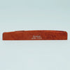 An orange-brown acoustic guitar bridge saddle made of cow bone with the name Guyker ATR-7231 engraved on it.