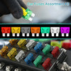A hand holds a green car fuse assortment kit with puller and circuit tester components placed on a black electrical block.