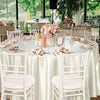 Elegant round satin tablecloth set for weddings featuring white chairs and floral centerpieces.