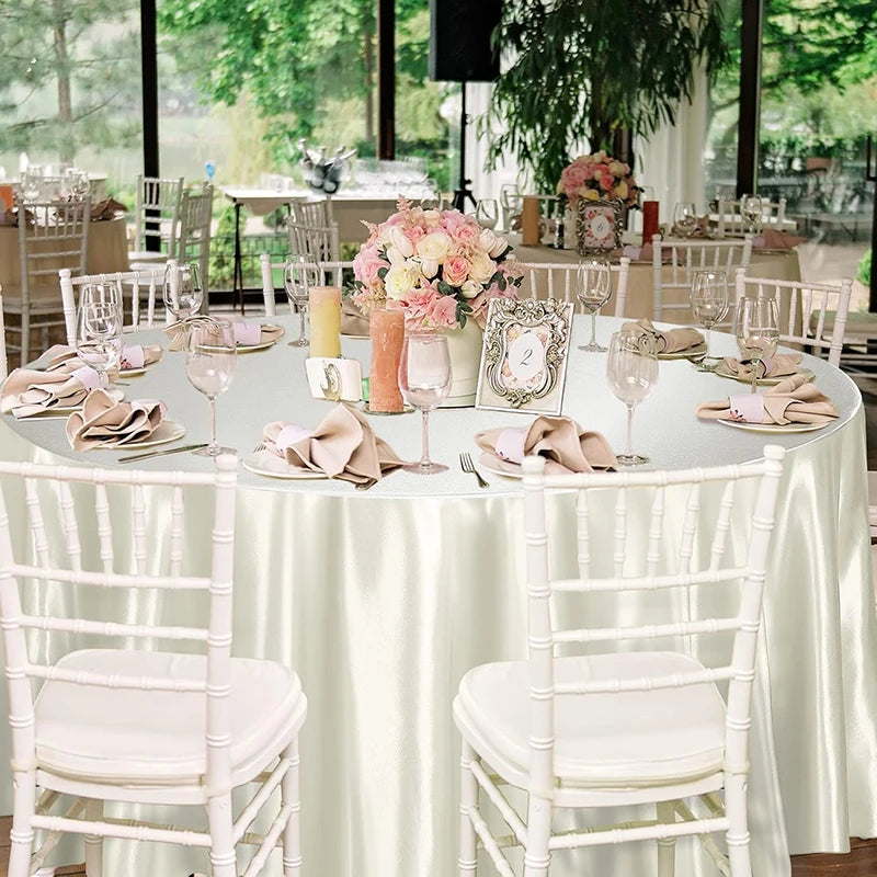 Elegant round satin tablecloth set for weddings featuring white chairs and floral centerpieces.