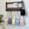 A collection of light-colored and pastel fabric crossbody bags hanging on a wooden shelf.