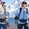 Two women hiking in snowy mountains with backpacks and fanny packs