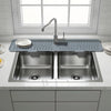 A stainless steel kitchen sink with a faucet and a silicone mat placed on the countertop.