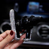 A hand holds a black crystal air vent car phone holder device.