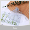 A set of organza drawstring jewelry gift bags in grey, featuring small plants and a leafy branch on a wooden surface.
