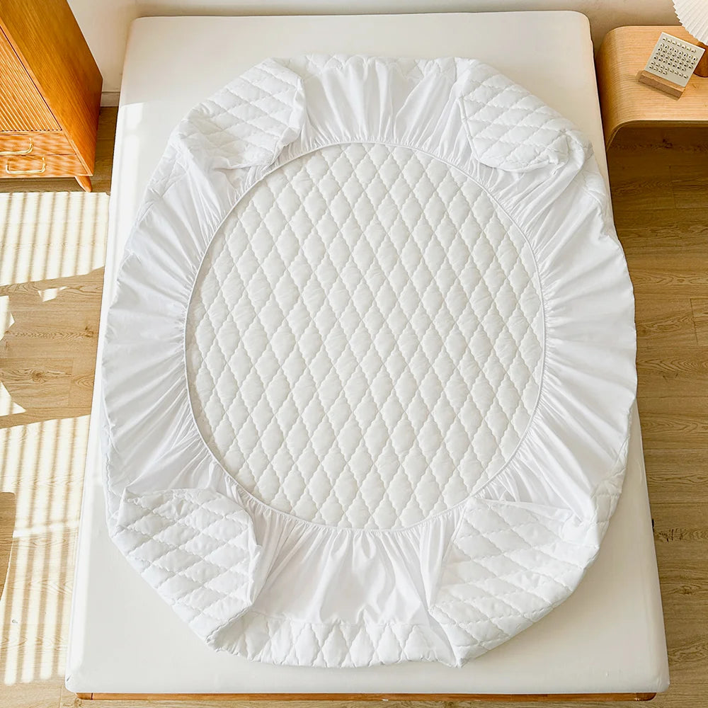White waterproof fitted mattress protector with quilted texture placed on a light-colored surface.