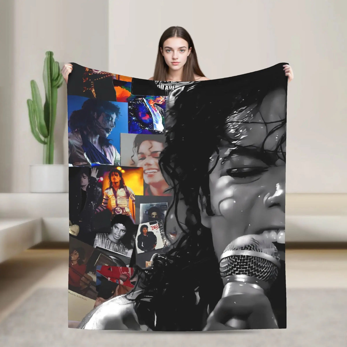 A person holds up a graphic plush throw blanket featuring various images of Michael Jackson.