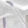 A silver extendable microfiber duster with a fluffy head hanging from the ceiling.