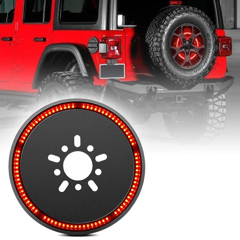 Close-up of a round LED brake light mounted on the rear of a red Jeep Wrangler with a large tire.
