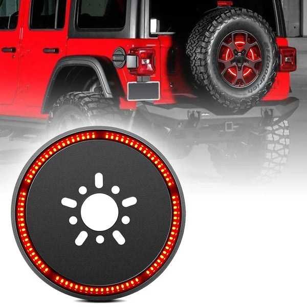Close-up of a round LED brake light mounted on the rear of a red Jeep Wrangler with a large tire.