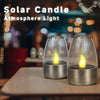 Two solar candle atmosphere lights glowing warmly on a wooden table.