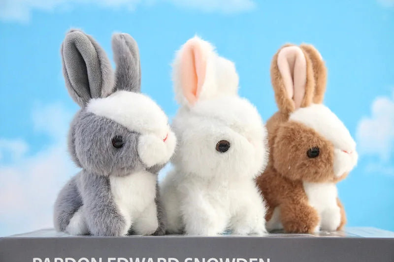 A set of three mini plush bunny toys with gray, white, and brown fur standing on a gray surface.